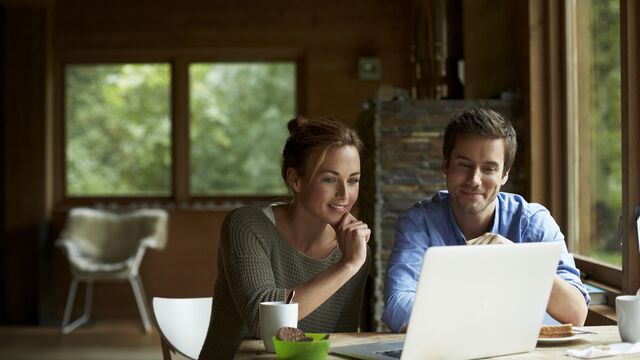 Et ungt par som sitter foran laptop og ser på sparingen sin sammen.